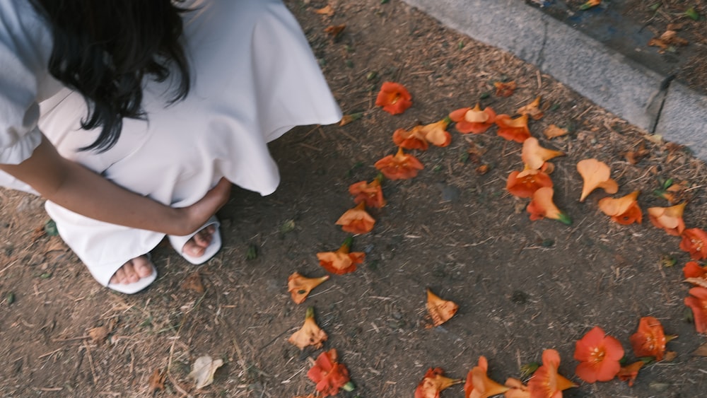 a woman sitting on the ground next to a bunch of flowers