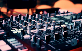 Close-up of DJ equipment with vibrant lighting and a focused DJ.