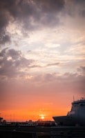 An aerial view of a large vessel docking smoothly alongside a bustling harbor at sunset.