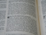 A close-up view of a page from a book with black text on a slightly yellowed background. The text appears to be from a Bible, containing passages such as 'Doom for the mountains of Israel.' The text is organized into paragraphs and verses with some headings in bold.
