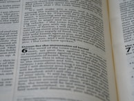 A close-up view of a page from a book with black text on a slightly yellowed background. The text appears to be from a Bible, containing passages such as 'Doom for the mountains of Israel.' The text is organized into paragraphs and verses with some headings in bold.