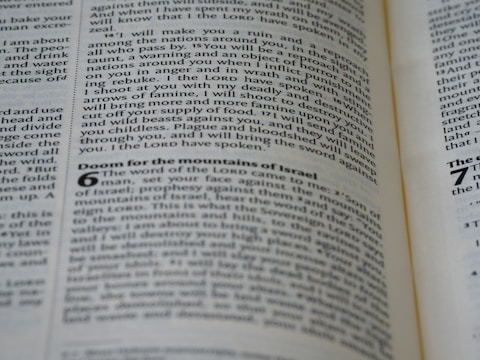 A close-up view of a page from a book with black text on a slightly yellowed background. The text appears to be from a Bible, containing passages such as 'Doom for the mountains of Israel.' The text is organized into paragraphs and verses with some headings in bold.