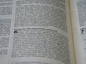 A close-up view of a page from a book with black text on a slightly yellowed background. The text appears to be from a Bible, containing passages such as 'Doom for the mountains of Israel.' The text is organized into paragraphs and verses with some headings in bold.