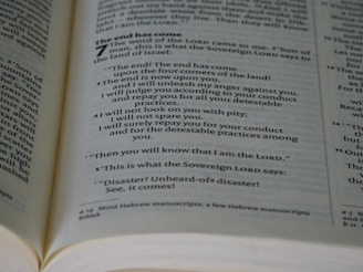 An open book showing a passage with biblical text. The page is filled with neatly aligned black text on white paper, with bold headings and numbers indicating chapters and verses.