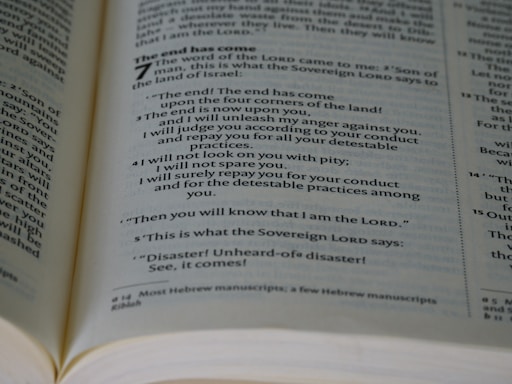 An open book showing a passage with biblical text. The page is filled with neatly aligned black text on white paper, with bold headings and numbers indicating chapters and verses.