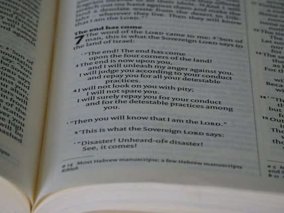 An open book showing a passage with biblical text. The page is filled with neatly aligned black text on white paper, with bold headings and numbers indicating chapters and verses.