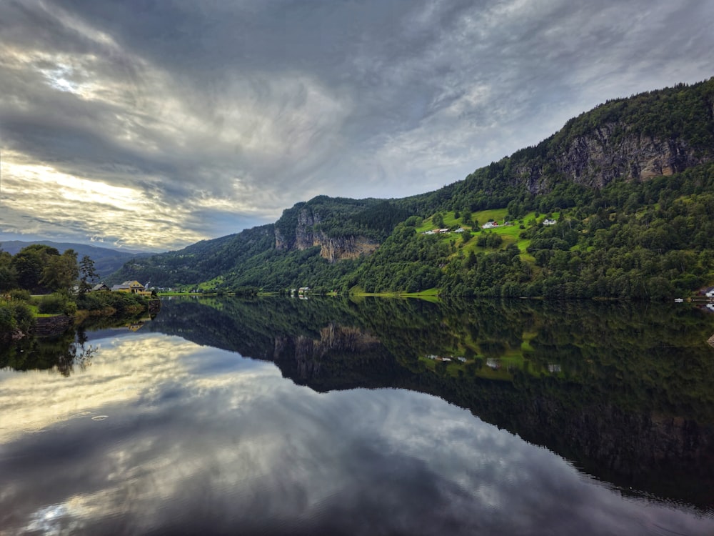 a body of water surrounded by mountains under a cloudy sky