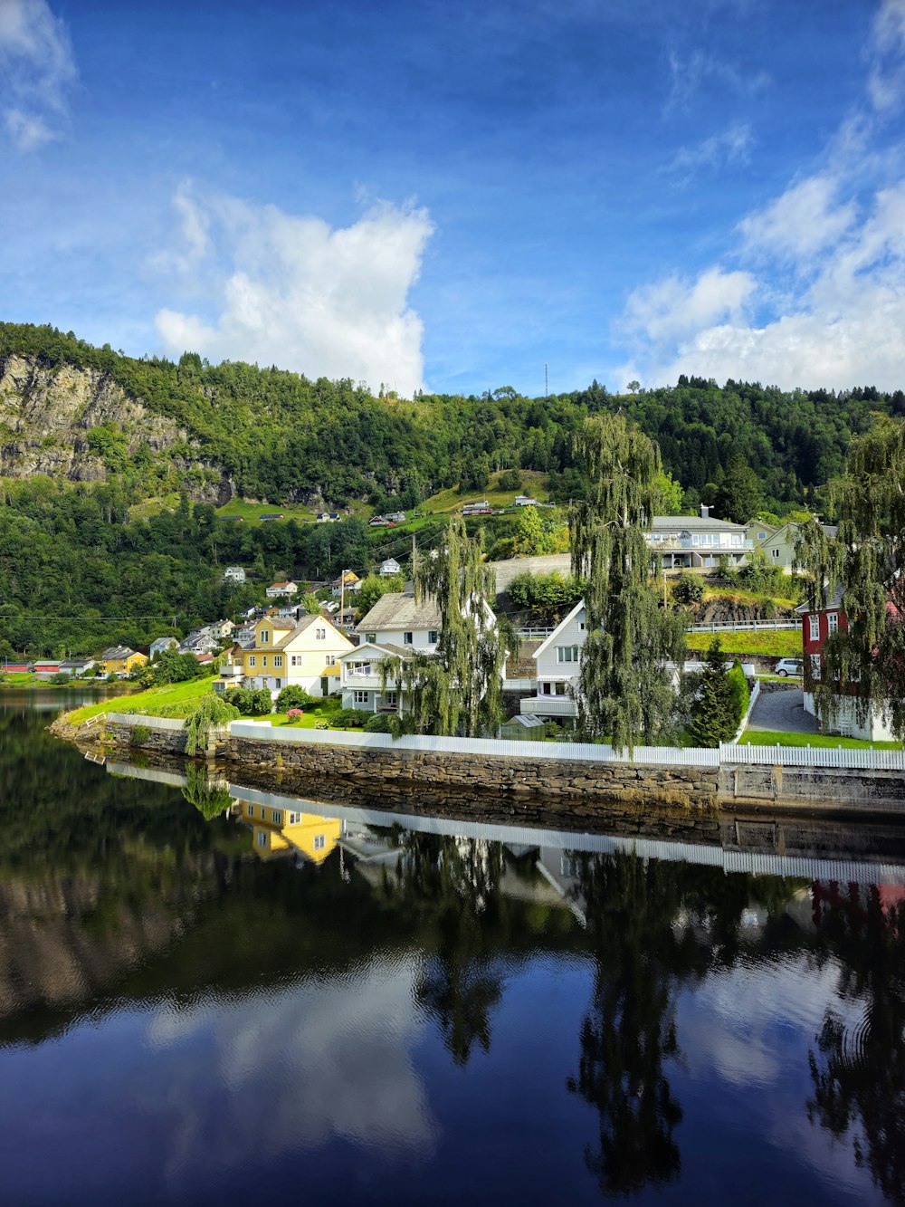 a body of water with houses on a hill in the background