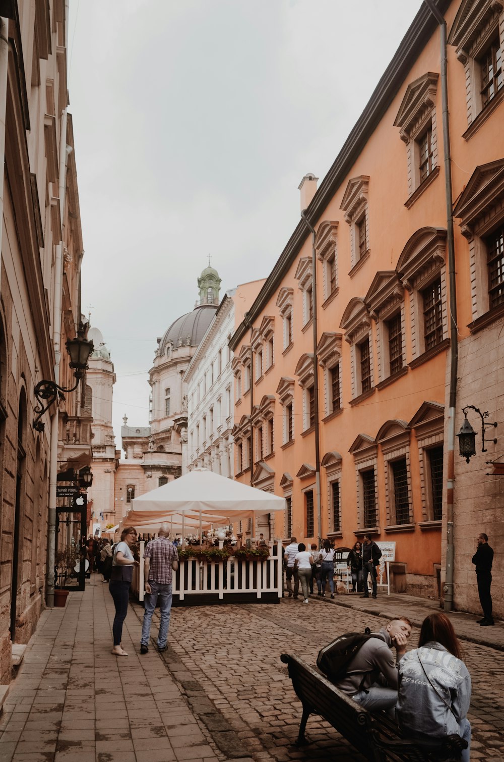 a group of people walking down a street next to tall buildings