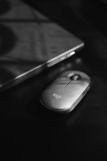 A compact wireless mouse on a sleek desk next to a laptop, bathed in warm afternoon light.