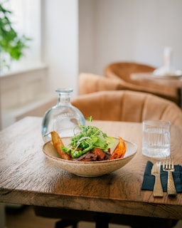 A rustic wooden table showcasing a colorful salad with fresh seasonal vegetables in a minimalist setting