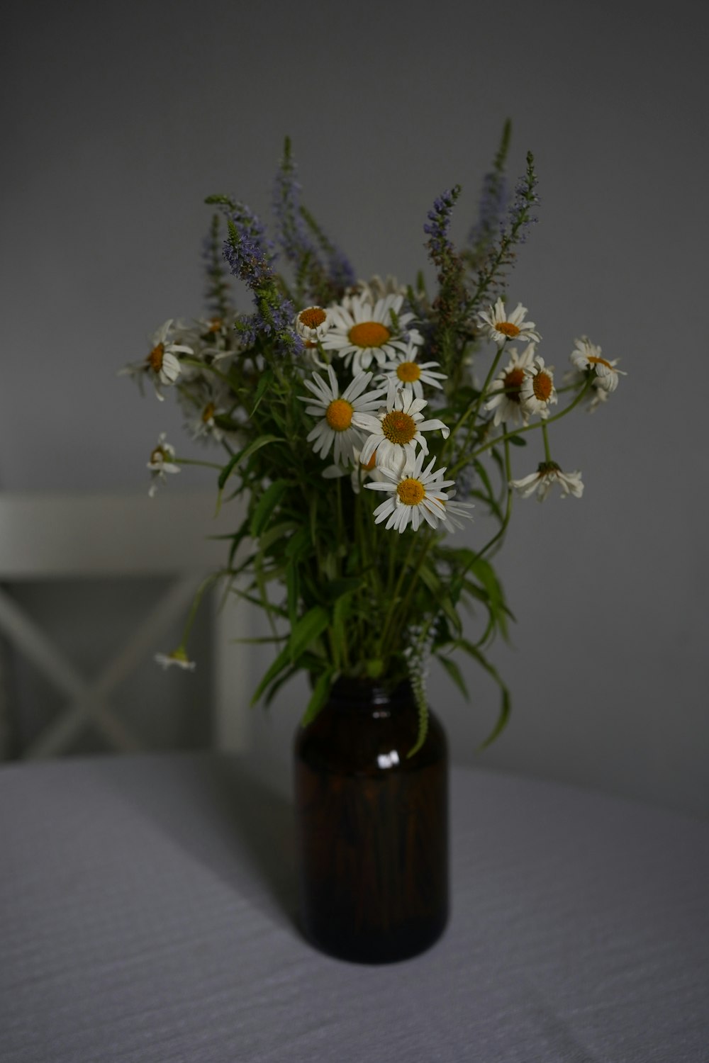 a vase filled with lots of white and yellow flowers