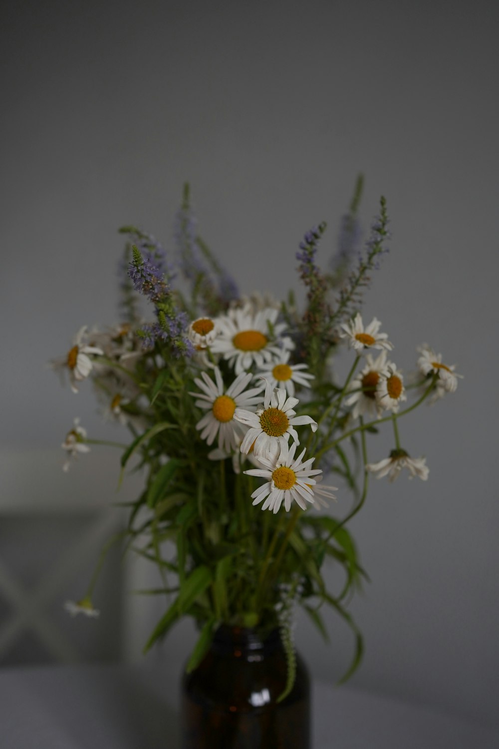 a vase filled with lots of white and yellow flowers