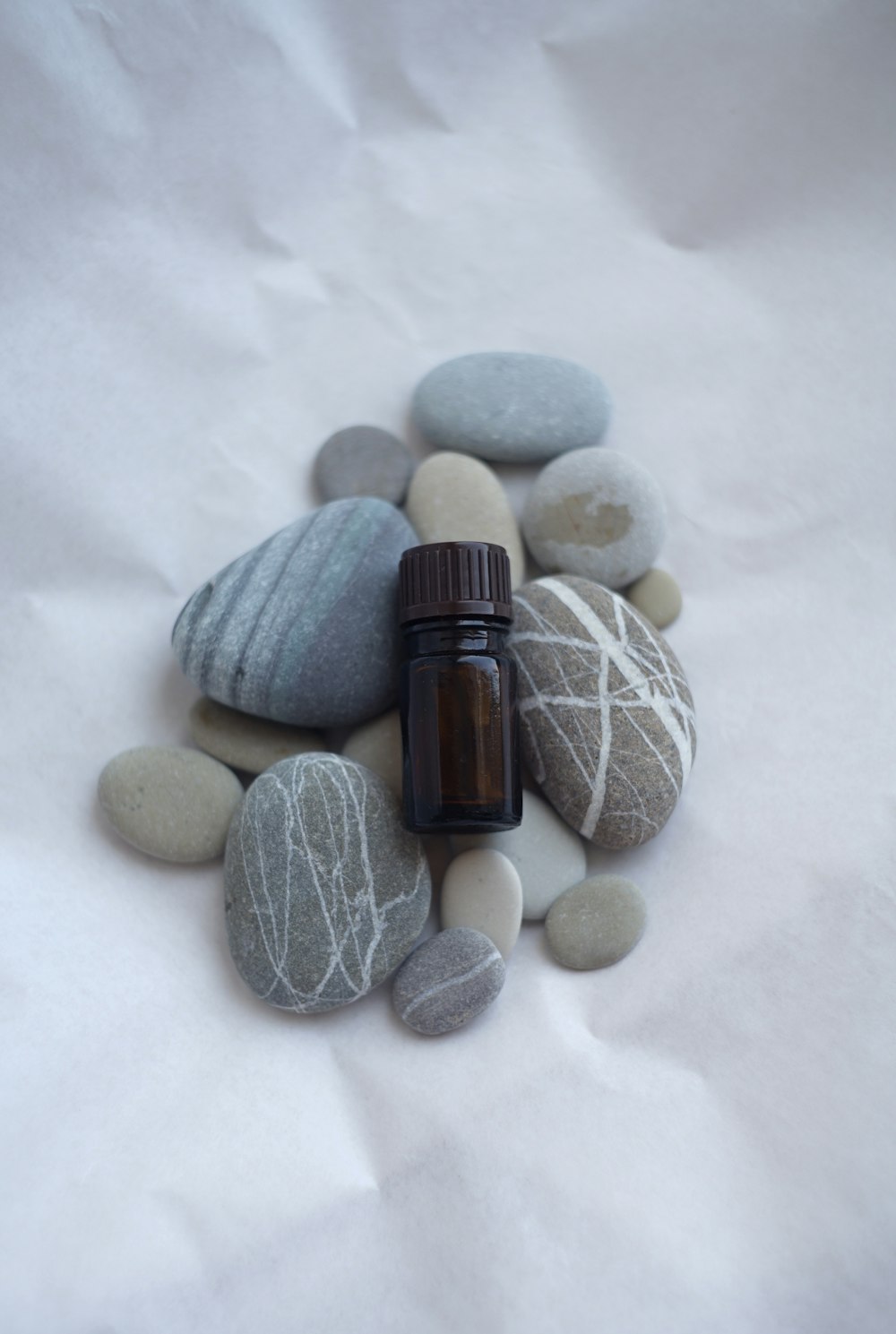 a bottle of essential oil sitting on a pile of rocks