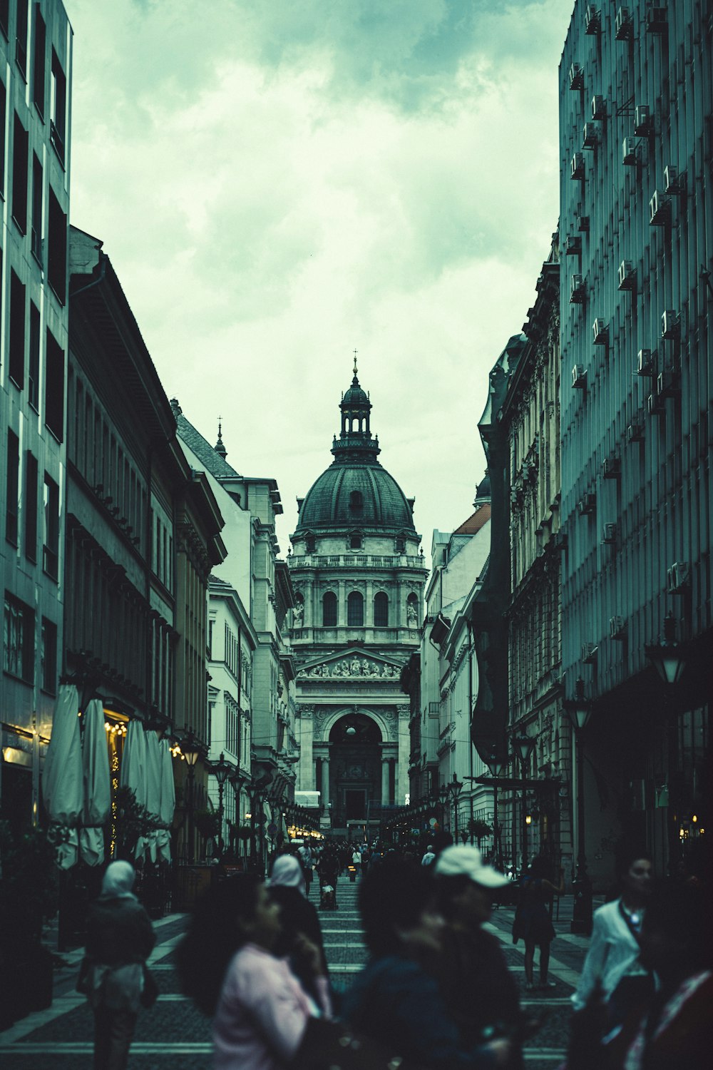 a group of people walking down a street next to tall buildings