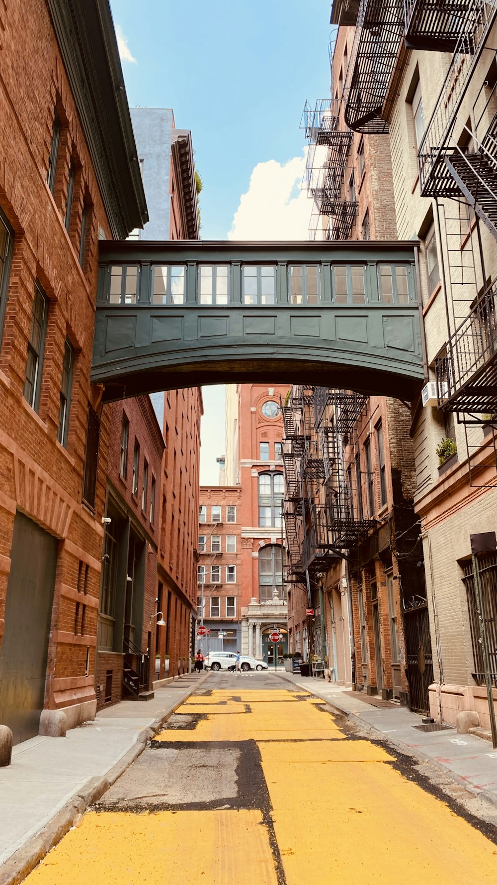 a narrow city street with a bridge over it