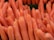 A collection of vibrant orange carrots tightly packed together, with a focus on their elongated, tapered forms.