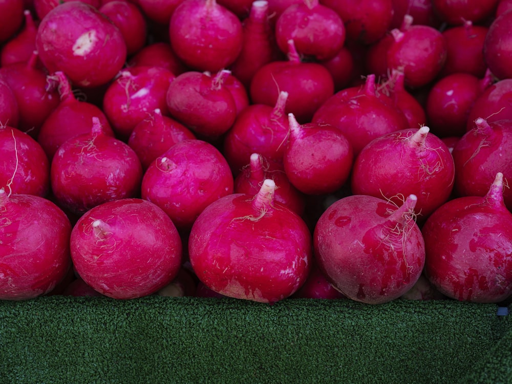 a pile of red radishes sitting on top of a green surface