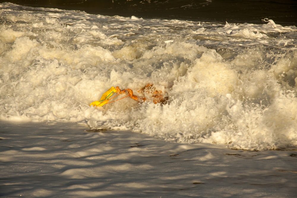 a yellow object floating on top of a wave in the ocean