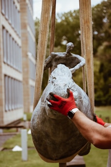 A professional staff member carefully packaging a valuable sculpture.
