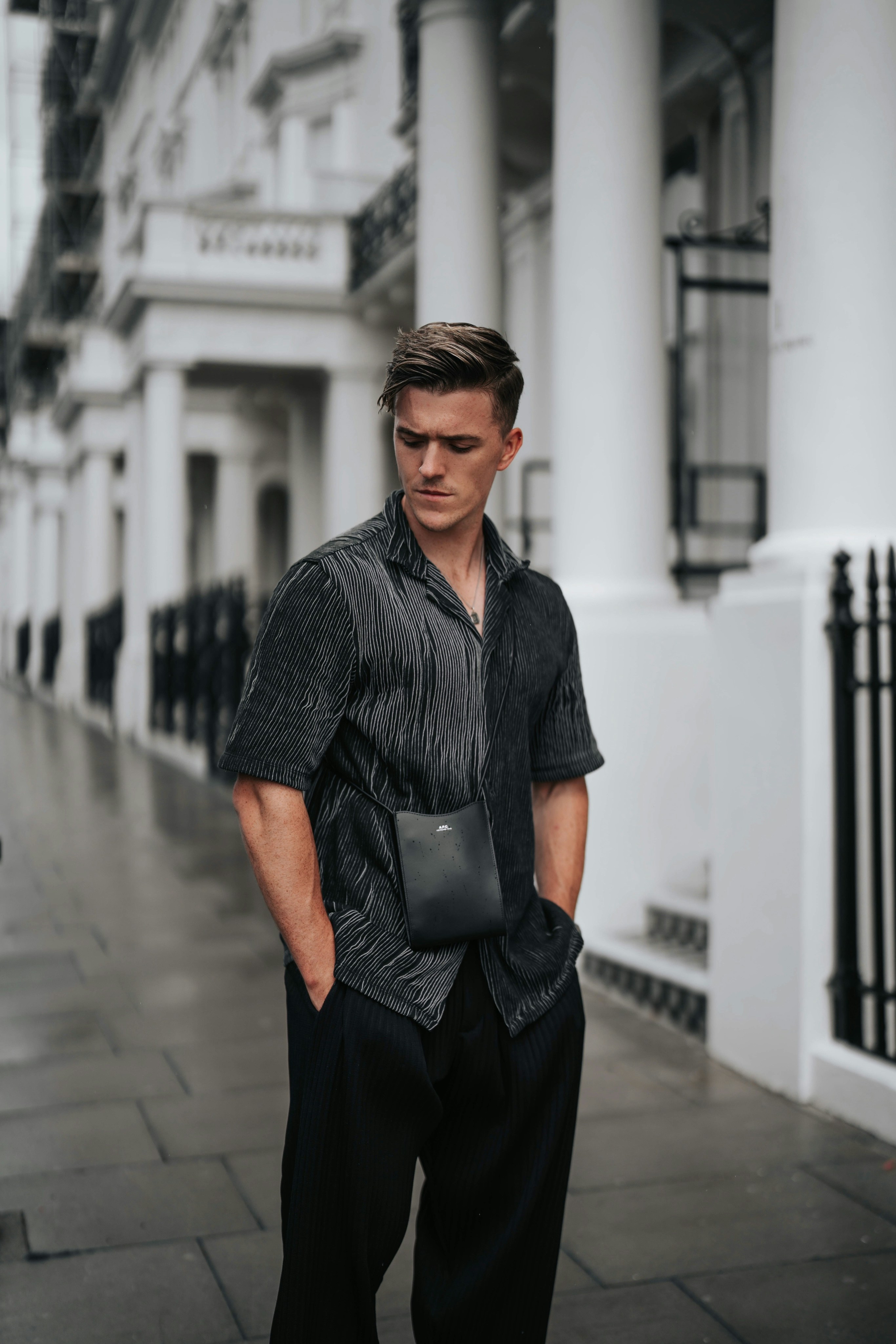 a man standing on a sidewalk in front of a building