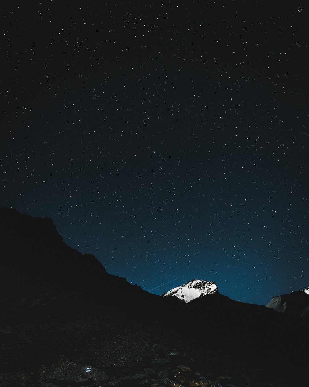 the night sky with stars above a mountain range