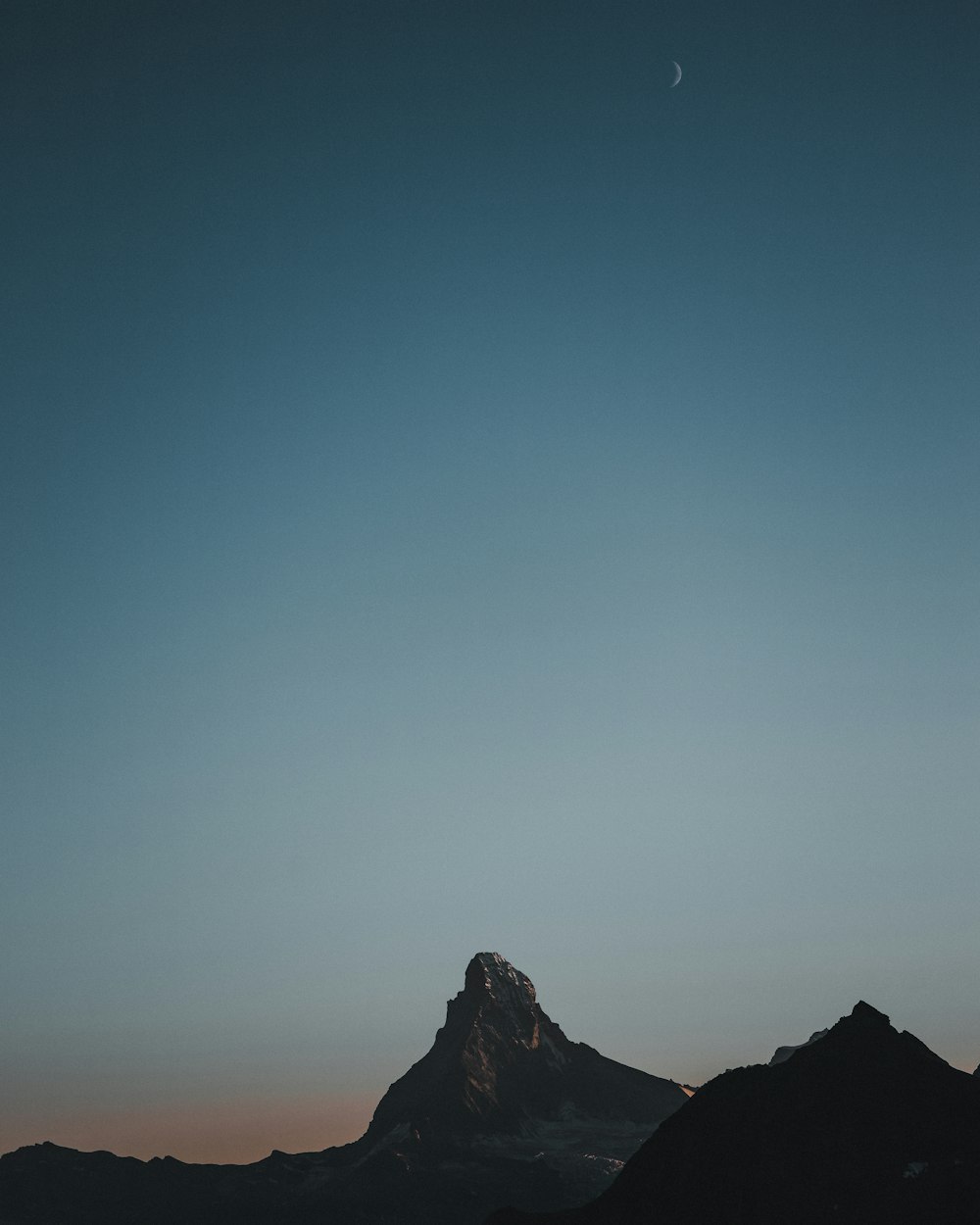 a mountain with a moon in the sky