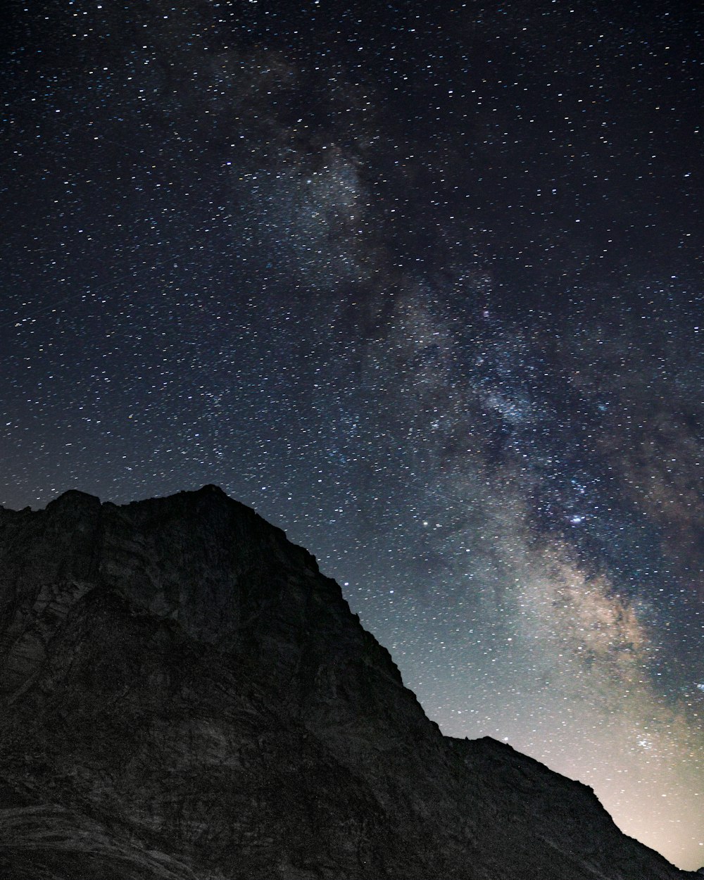 the night sky is filled with stars above a mountain