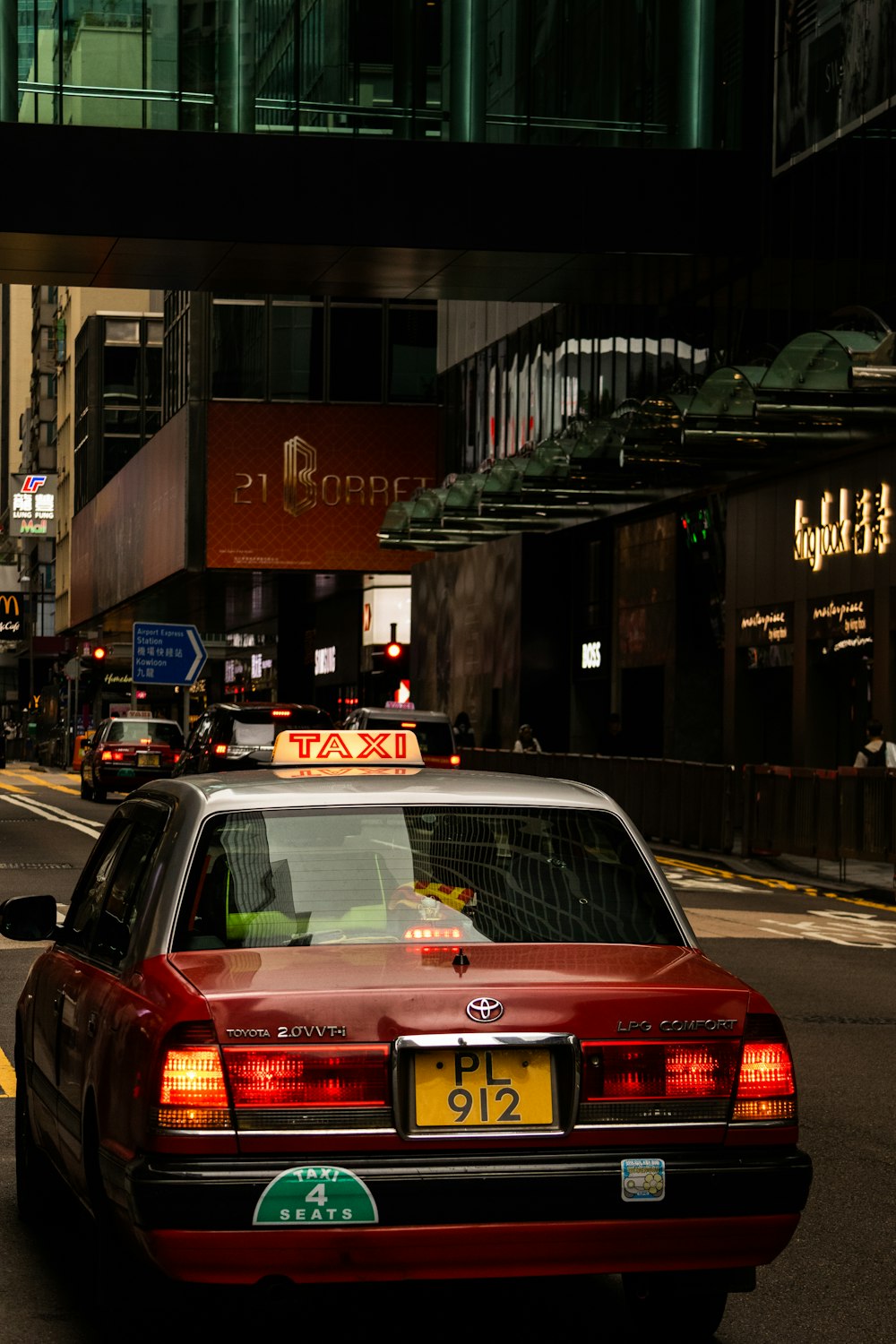 a red car driving down a street next to tall buildings