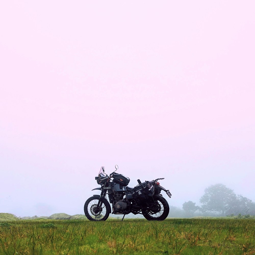a motorcycle parked in a field on a foggy day