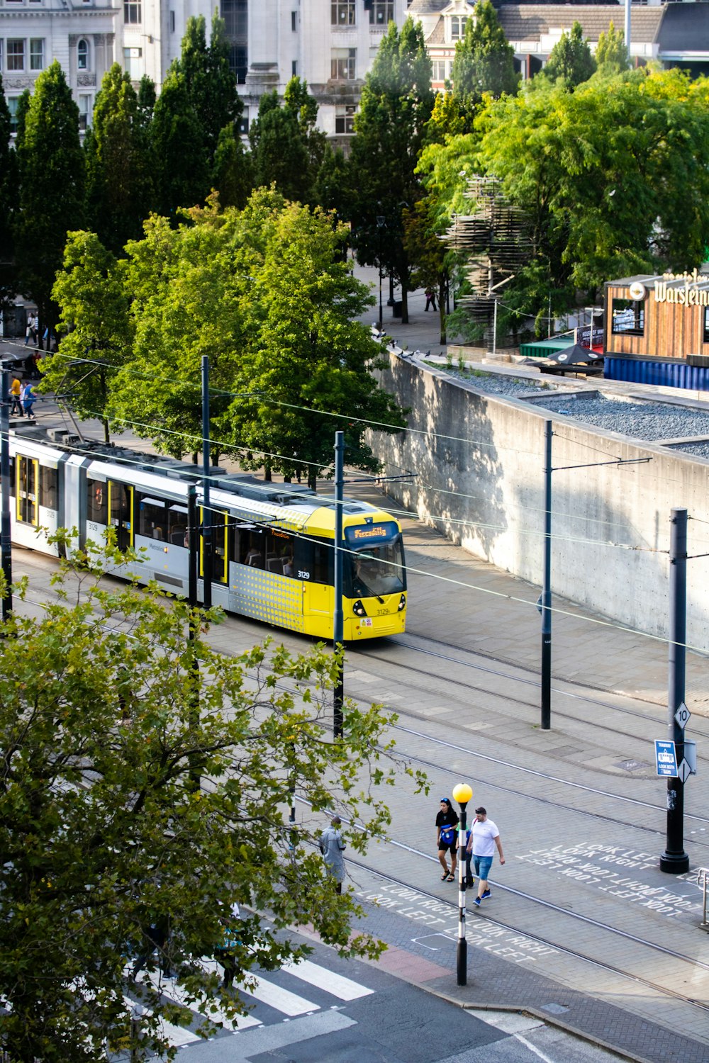 a yellow train traveling down a street next to tall buildings