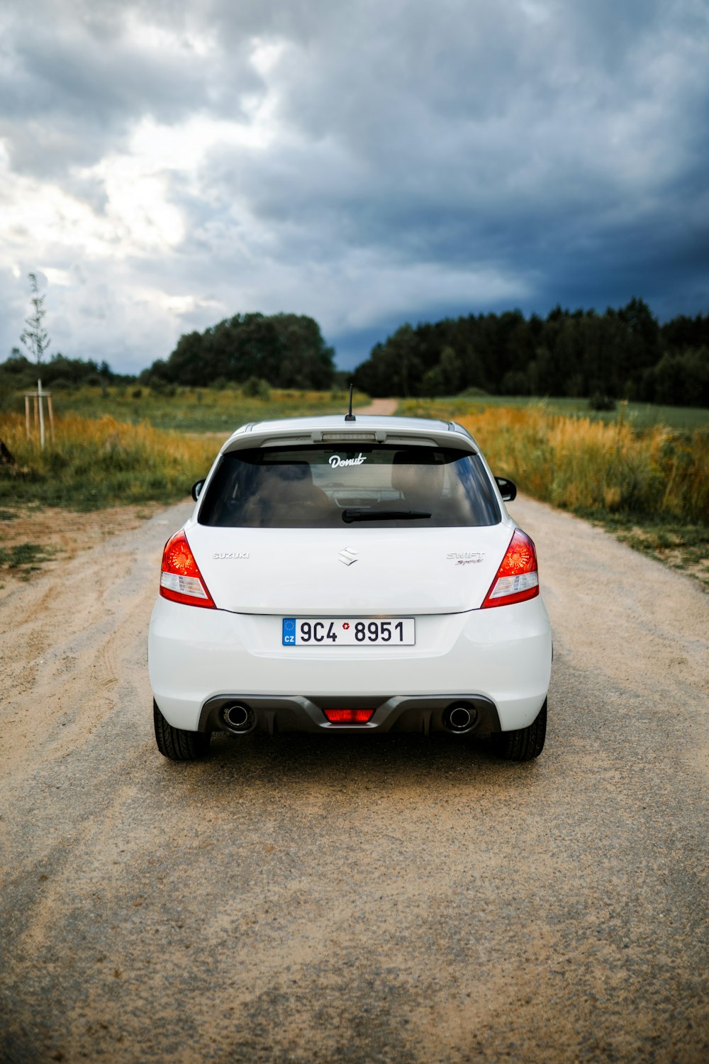 a white car parked on the side of a dirt road