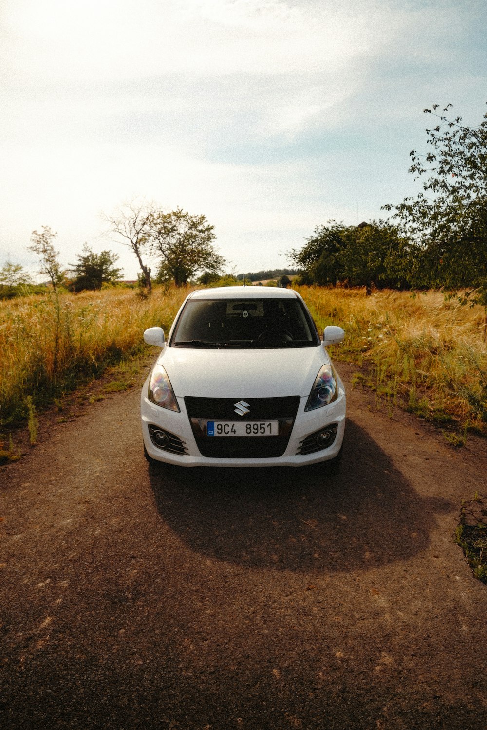 a white car parked on a dirt road