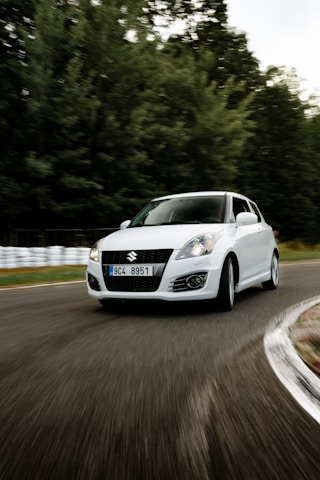 A sleek Suzuki Swift cruising through Chennai city streets during the day.