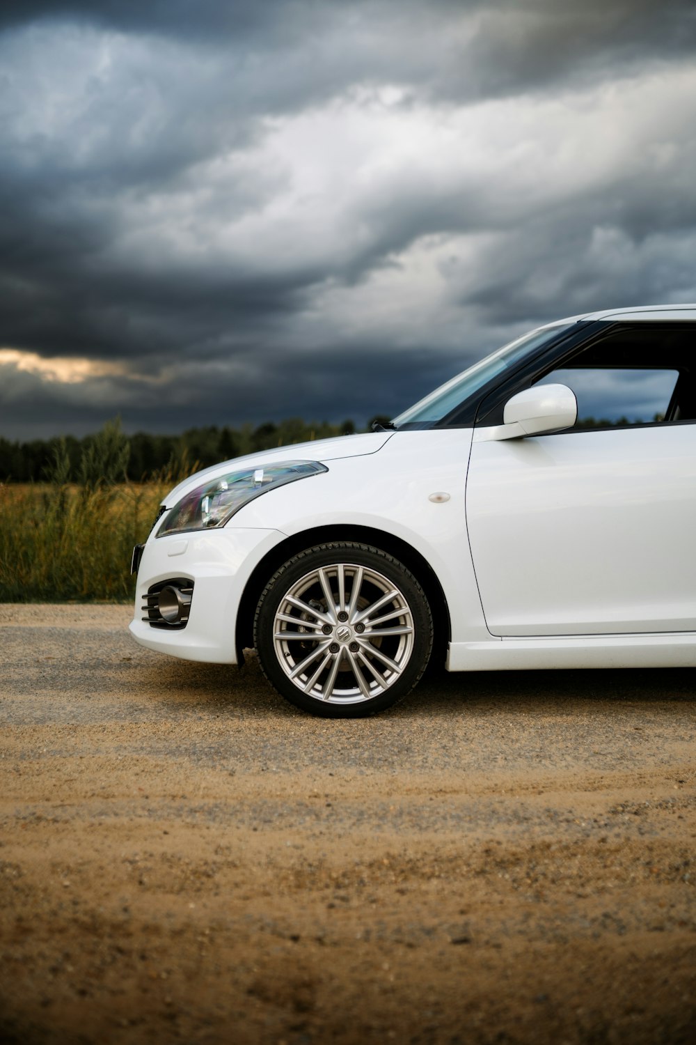 a white car parked in a parking lot under a cloudy sky