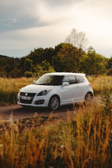 a small white car driving down a dirt road