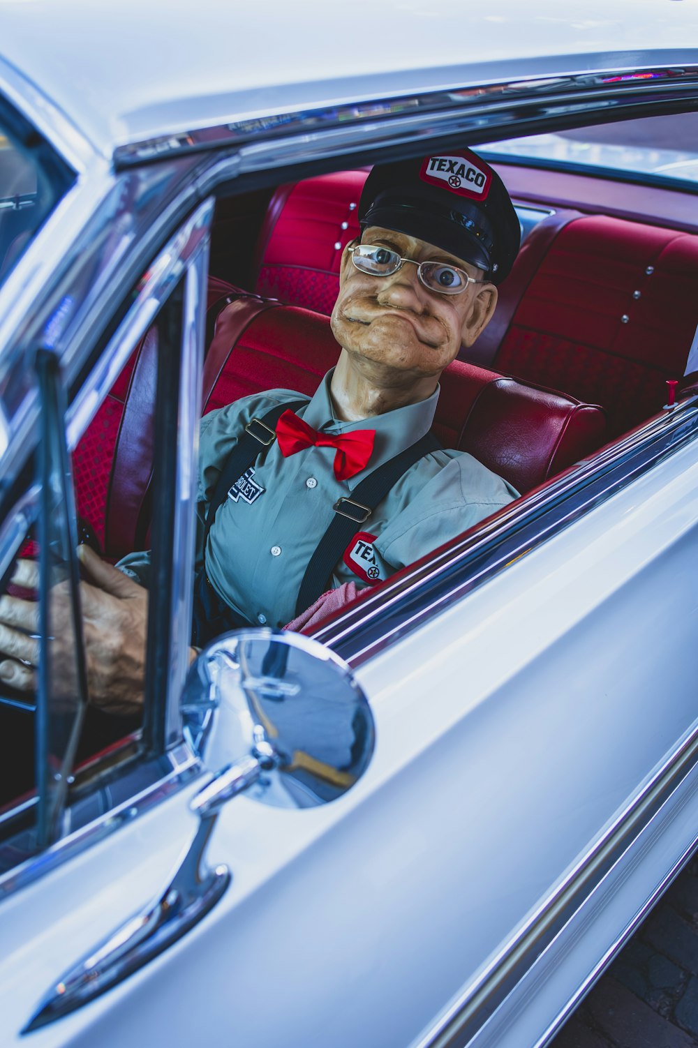 a man sitting in a car wearing a hat and bow tie