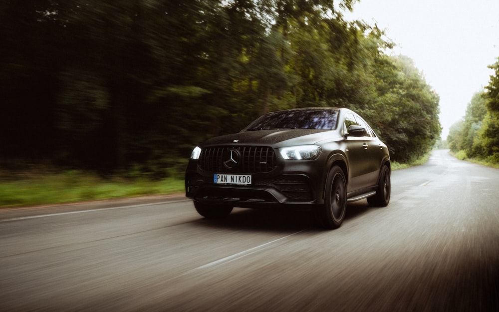 a black mercedes suv driving down a country road