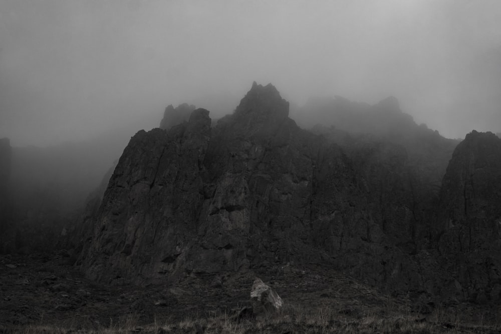 a black and white photo of a mountain in the fog