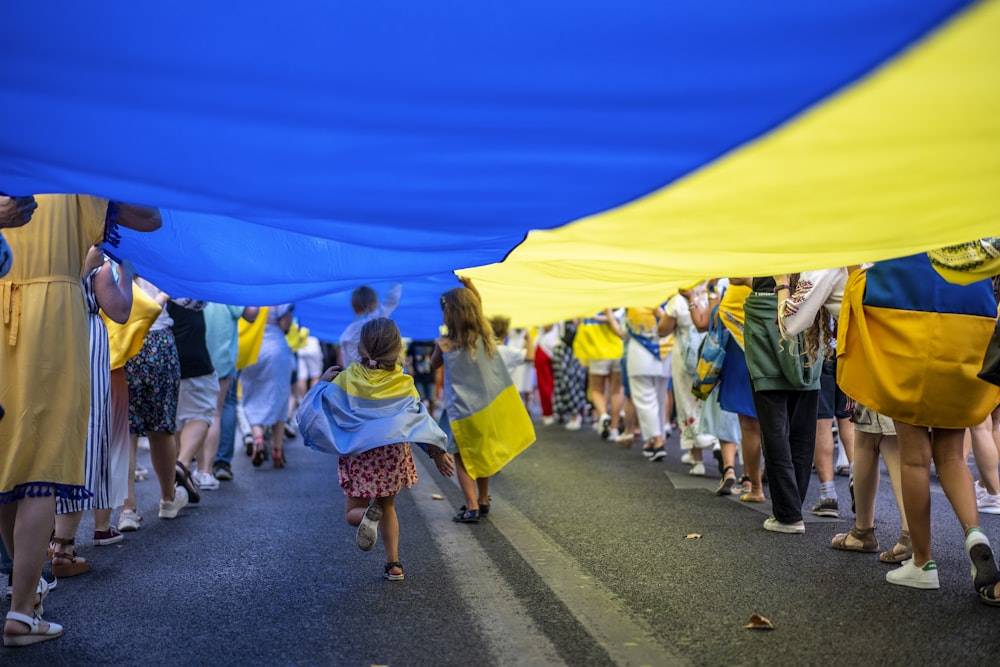 a group of people walking down a street under a blue and yellow tent