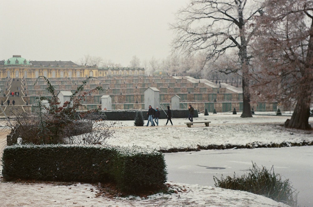 a couple of people walking across a snow covered field