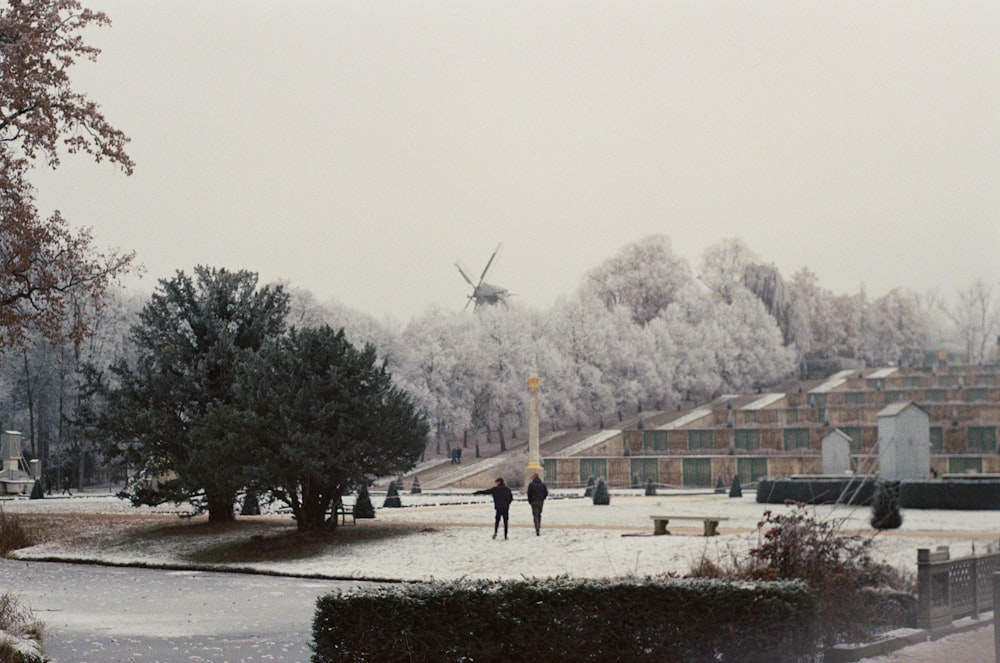Deux personnes marchant dans un parc enneigé avec un moulin à vent en arrière-plan