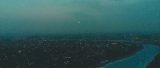 A panoramic view of a glacial river shining under an electric blue twilight sky.