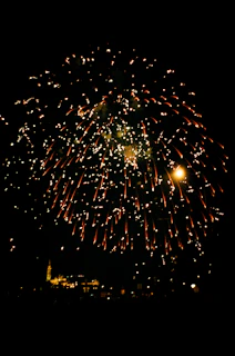 A dazzling burst of colorful fireworks lighting up the night sky over a romantic cityscape.