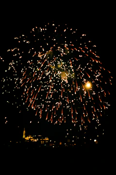 A vibrant burst of colorful fireworks illuminating a night sky over a city skyline.
