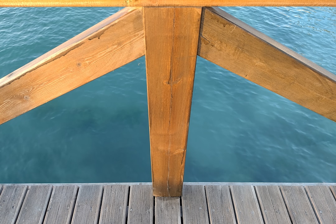 a close up of a wooden dock with water in the background, Closeup of wooden fence