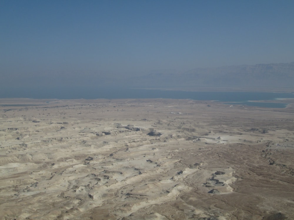 an aerial view of a desert with a body of water in the distance