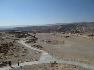 A traveler walking through the ruins of an ancient Saudi city surrounded by desert hills.