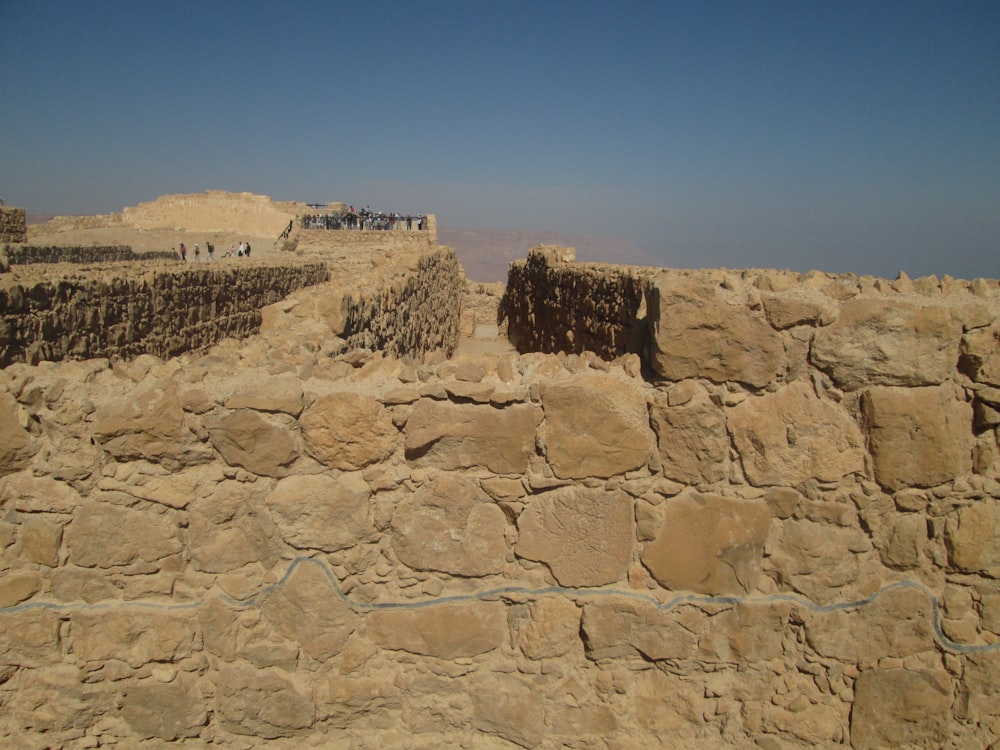 un muro de piedra con una fila de personas de pie encima de él