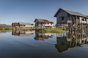 Exterior view of Na Can homestay with traditional stilt houses under blue sky.